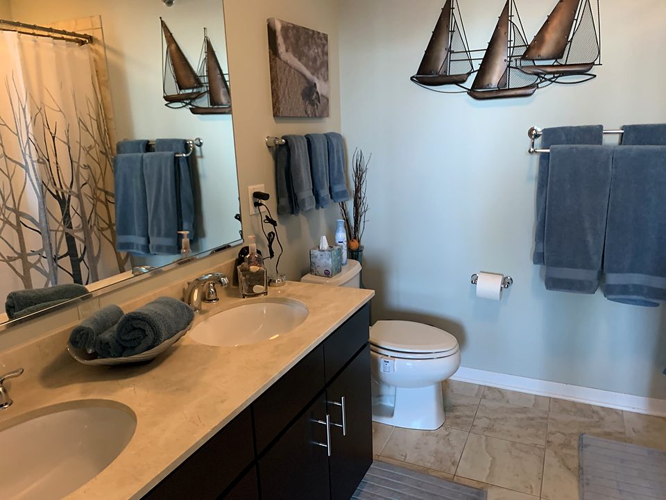 A double-vanity bathroom with folded towels on the counter and fresh towels on the rail