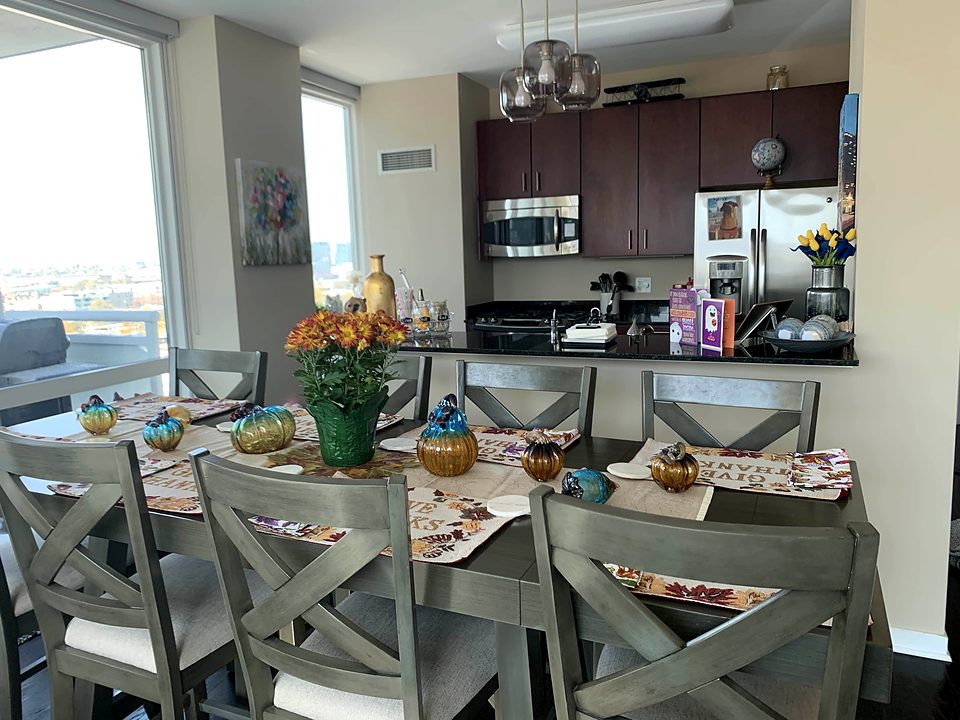 A dining table laid for autumn beside an open kitchen, city view through the window